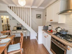 une cuisine avec des armoires blanches, une table et un comptoir dans l'établissement Dove Cottage, à Pickering