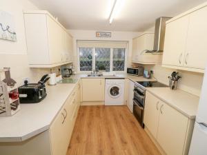 a kitchen with white cabinets and a dishwasher at 4 Ty Rhosyn in Porthmadog
