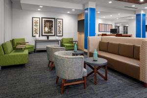 a waiting room with a couch and chairs and tables at Holiday Inn Express & Suites Wilmington West - Medical Park by IHG in Wilmington