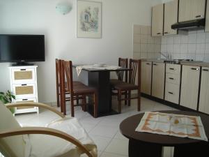 een keuken met een tafel en stoelen en een televisie bij Apartments Villa Kosović in Dubrovnik
