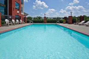 a large swimming pool with chairs and a building at Holiday Inn Express Hotel & Suites Olive Branch, an IHG Hotel in Olive Branch