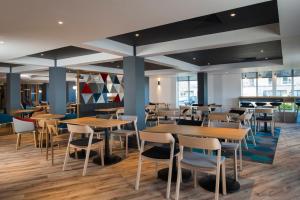 a restaurant with wooden tables and chairs at Holiday Inn Express Edinburgh - Leith Waterfront by IHG in Edinburgh