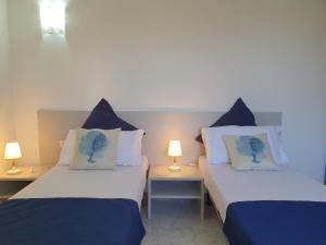 two beds with blue and white pillows in a room at Villette Miramare in Budoni