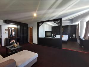 ein Wohnzimmer mit einem Sofa, einem Bett und einem Spiegel in der Unterkunft Nana Buri Hotel in Chumphon