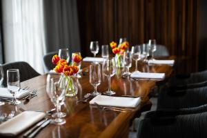Kimpton Hotel Palomar Philadelphia, an IHG Hotel في فيلادلفيا: طاولة خشبية طويلة مع كؤوس النبيذ والزهور عليها