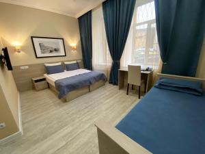 a hotel room with two beds and a table and a window at Apart-Hotel Oficer in Saint Petersburg