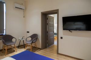 Zimmer mit 2 Stühlen und einem Flachbild-TV in der Unterkunft Hotel IRIS in Taschkent