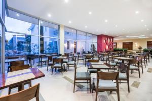 Holiday Inn Express Quito, an IHG Hotel في كيتو: مطعم بطاولات وكراسي ونوافذ كبيرة