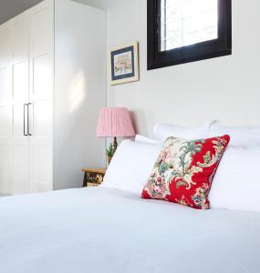 a bedroom with a white bed with a red pillow at The Ridge Eco-Cabins - A Secret Place to Slow Down in Gloucester