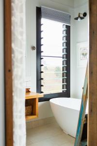 a bathroom with a white tub and a window at The Ridge Eco-Cabins - A Secret Place to Slow Down in Gloucester