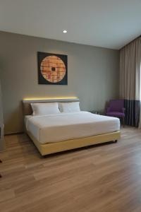 a bedroom with a large bed and a purple chair at Abell Hotel in Kuching