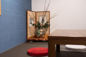Cette chambre comprend un vase et une table avec un tabouret rouge. dans l'établissement Tsukuyomi Higashiyama, à Kanazawa