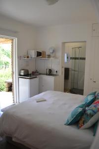 a white bedroom with a bed and a kitchen at Woodlands Retreat in Clarens