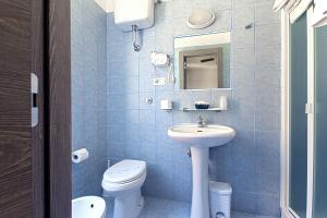bagno piastrellato blu con servizi igienici e lavandino di Hotel La Scaletta a Lido di Ostia