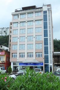 a tall building with cars parked in front of it at Cihan Hotel in Hopa