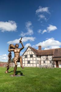 Eine Statue eines Mannes, der im Gras vor einem Gebäude steht. in der Unterkunft Eckington Manor in Pershore