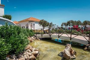 uma ponte sobre um rio com pedras e plantas em Mitsis Rodos Maris em Kiotari