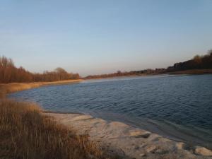 una gran masa de agua junto a un campo en Domek letniskowy - Świętne nad jeziorem Wilczyńskim, en Wilczyn