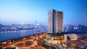 un grand bâtiment à côté d'une rivière dans une ville dans l'établissement InterContinental Shanghai Expo, an IHG Hotel, à Shanghai