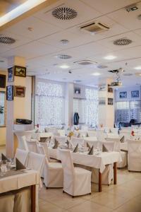 Hotel Galaksija Trebnje في Trebnje: غرفة طعام مع طاولات بيضاء وكراسي بيضاء