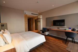 1 dormitorio con 1 cama y escritorio con TV en Holiday Inn Express Hangzhou Binjiang, an IHG Hotel en Hangzhou