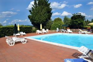 a swimming pool with chairs and umbrellas next to it at La Canonica in San Giovanni dʼAsso