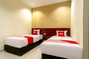 two beds in a hotel room with red pillows at Capital O 1585 Ring Road Residence in Medan