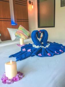 a blue towel on a bed next to a candle at Rimnatee Resort Trang in Trang