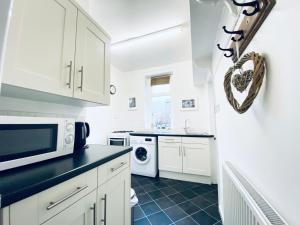 a kitchen with white cabinets and a black tile floor at Hill Cottage in Haworth