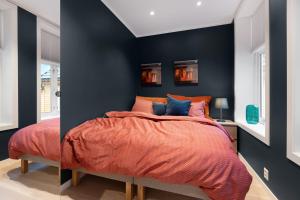 a bedroom with black walls and a bed with orange sheets at Keyser Apartments 6 in Bergen