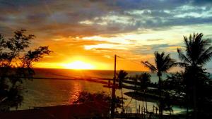 um pôr-do-sol sobre um corpo de água com palmeiras em Le Grand Bleu Hotel em Wok Tum