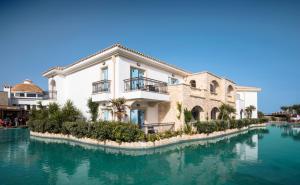 a large white house with water in front of it at Mitsis Selection Laguna in Hersonissos