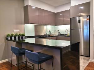 a kitchen with a counter with two stools and a refrigerator at ELECTUS HOME at Vista Residences Genting - FREE WiFi & TV Box & Parking in Genting Highlands