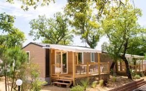 a tiny house with a porch and a deck at Camping Sunelia L'Argentière in Cogolin
