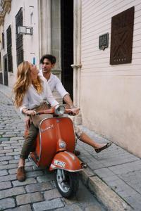 um homem e uma mulher sentados numa scooter em CoolRooms Palacio Villapanés em Sevilha