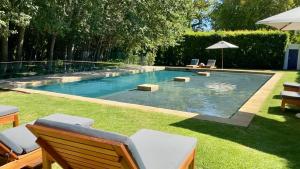 a swimming pool in a yard with chairs and an umbrella at La Paris Estate in Franschhoek