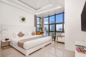 a white bedroom with a large bed and large windows at Star City Riverside Hotel By Haviland in Da Nang