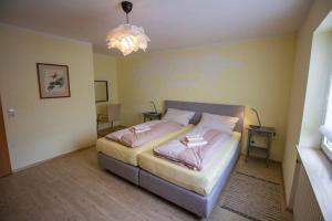 Un dormitorio con una cama con sábanas rosas y una lámpara de araña. en Ferienwohnung Habermehl en Oppenau