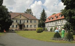 een groot huis met twee mensen ervoor bij Hotel Kavaliershaus/Schloss Bad Zwesten in Bad Zwesten
