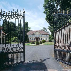 um portão para uma mansão com uma casa ao fundo em Hotel Kavaliershaus/Schloss Bad Zwesten em Bad Zwesten