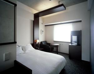 a hotel room with a bed and a television at Furano Natulux Hotel in Furano