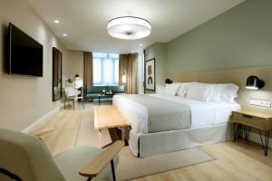ein Hotelzimmer mit einem großen Bett und einem Wohnzimmer in der Unterkunft Barceló Oviedo Cervantes in Oviedo