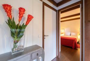 a vase of flowers on a table in a bedroom at Casa das Clivias in Ponta Delgada