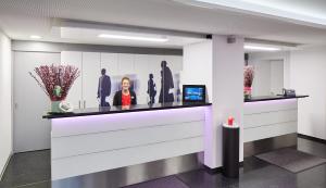 a woman standing at a counter in a lobby at Hotel Banana City Winterthur in Winterthur