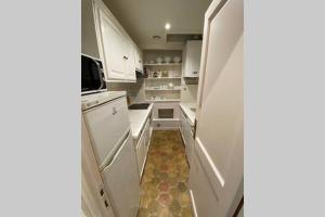 een kleine keuken met witte kasten en een koelkast bij Le Jeu de Paume à Beaune centre in Beaune