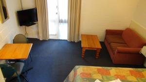 Habitación con sofá, mesa y TV. en Pathfinder Motel en Melbourne
