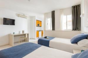 una camera d'albergo con due letti e una televisione di Apartamentos Vibra Panoramic a Ibiza Città