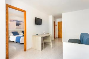 a room with a bed, desk and a television at Apartamentos Vibra Panoramic in Ibiza Town