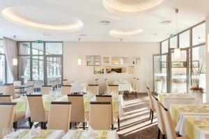 a restaurant with white tables and chairs and windows at Hotel Panorama in Trenčianske Teplice