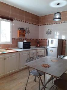 a kitchen with a table and chairs and a refrigerator at Diar Karim Djerba in Midoun